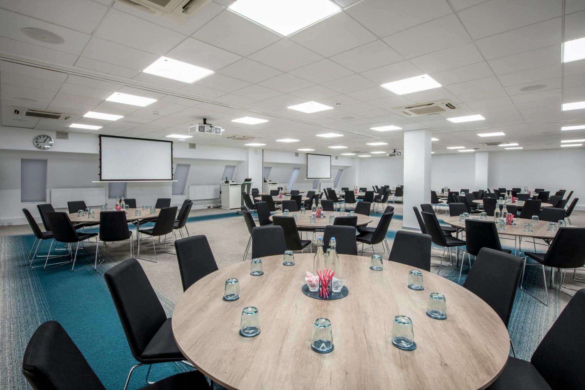 Versatile business center with round tables, ideal for conferences and networking events. - Banner