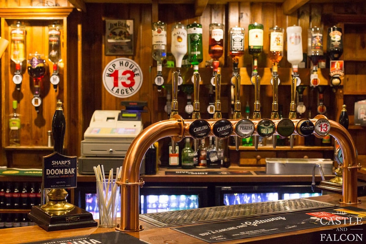 Well-stocked bar with polished taps in cozy Castle & Falcon for networking events.