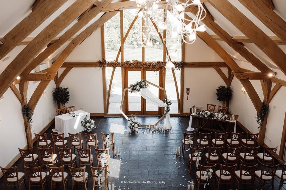 Gazebo in Mythe Barn, rustic beams and floral decor for elegant wedding ceremonies.