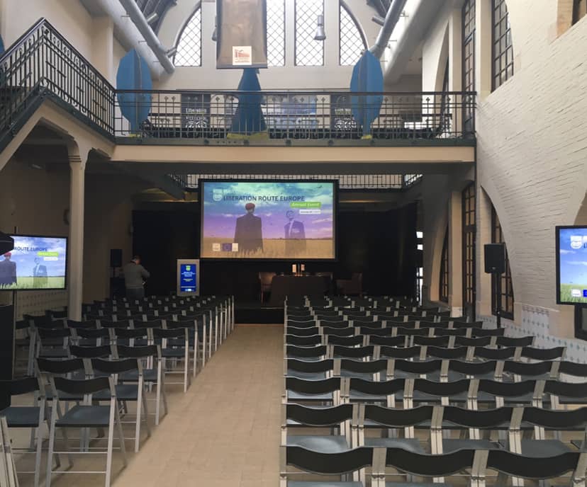 Event space with rows of chairs and large screen for conferences or seminars.