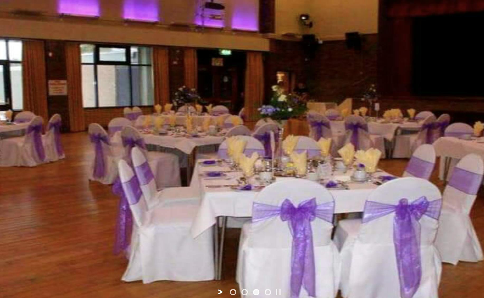 Elegant event space with white tables and purple sashes, perfect for weddings or gatherings.
