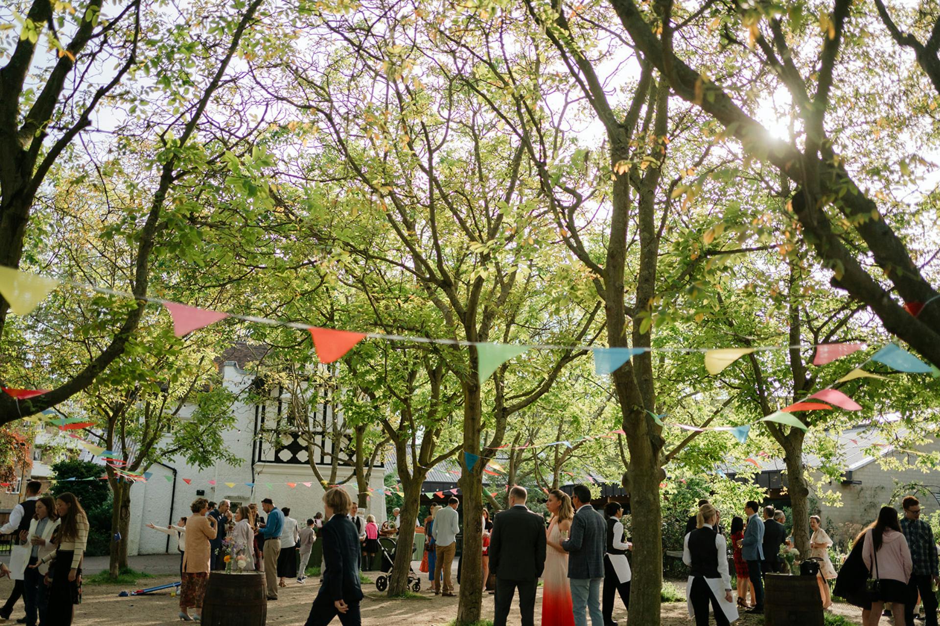 Vibrant outdoor event in Sands End courtyard with colorful bunting and elegant guests.