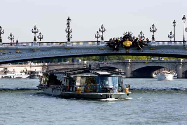 Le Diamant II boat under ornate bridge, perfect for corporate retreats and romantic dinners.
