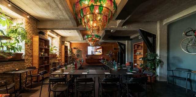Stylish ballroom with long table and vibrant chandeliers for creative events.
