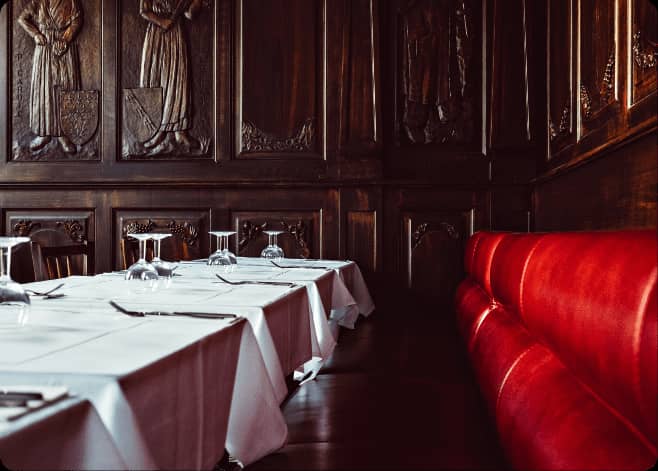 Elegant dining space with wooden paneling and plush red seating for upscale events.