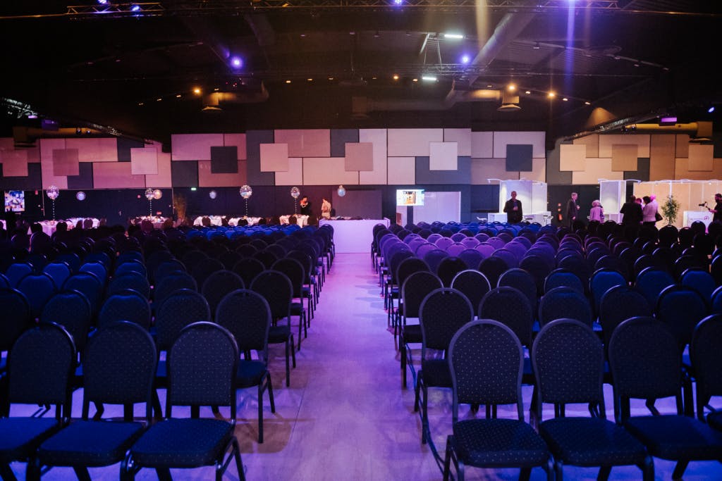 Spacious conference venue with blue chairs and dynamic lighting in Grand Paris.
