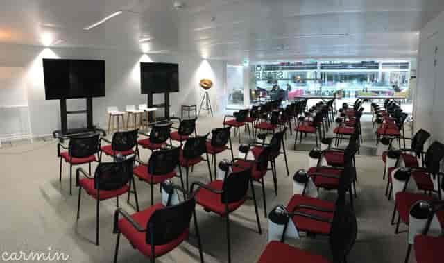 Central Room at STATION F, organized for workshops with red and black chairs and dual screens.
