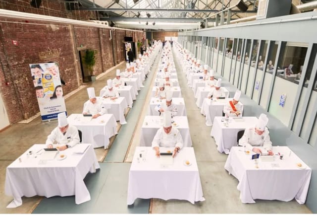 Culinary competition at Riverside Restaurant, chefs in white uniforms, spacious venue.
