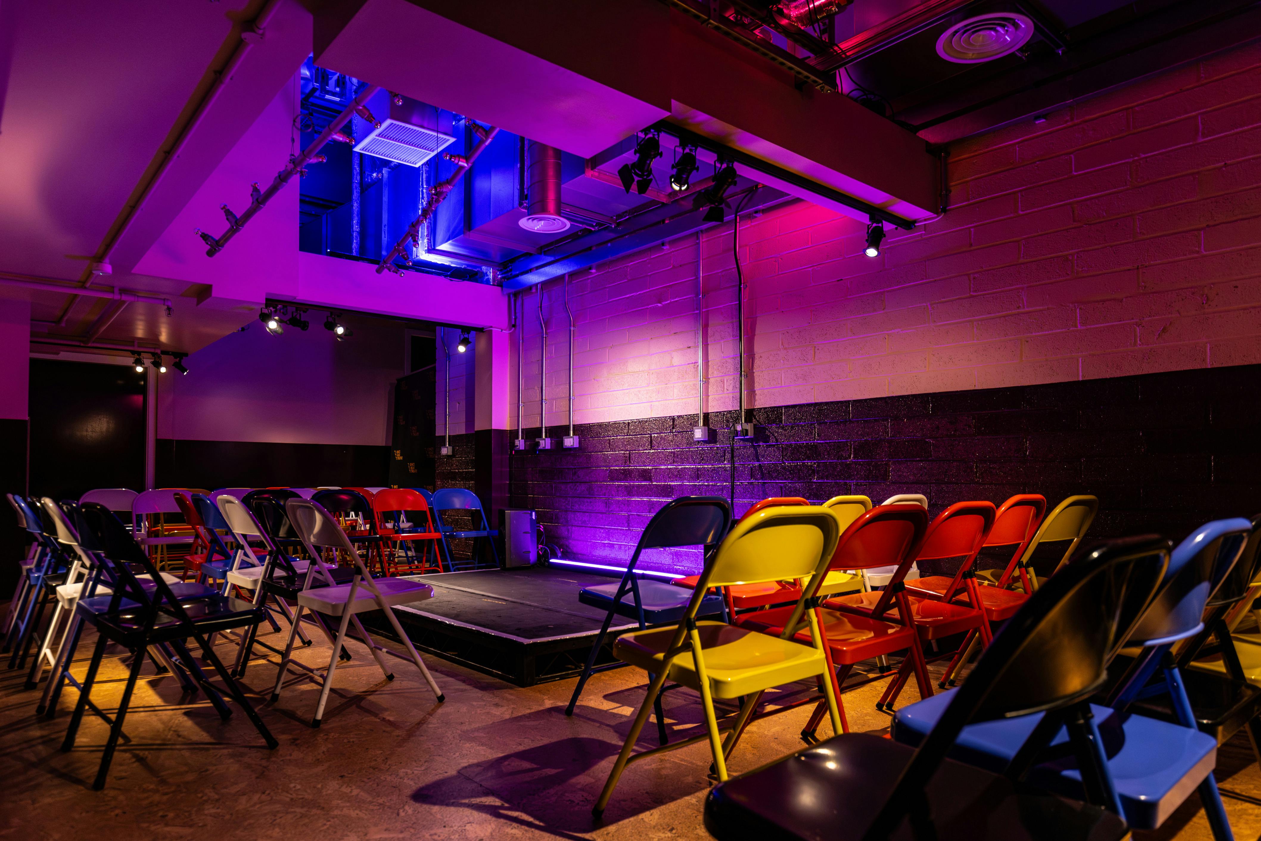 Intimate event space at King's Head Theatre with vibrant chairs and elevated stage.