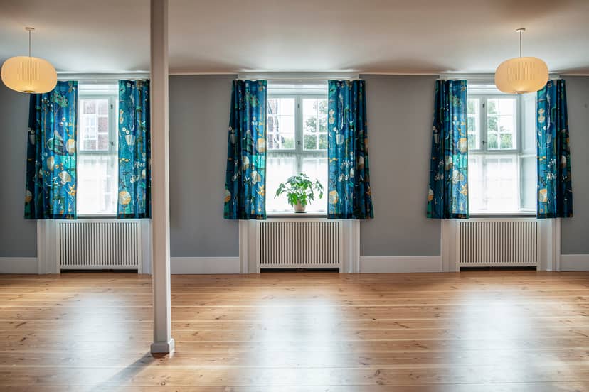 K. Larsen in a bright, versatile meeting space with floral curtains for workshops and gatherings.