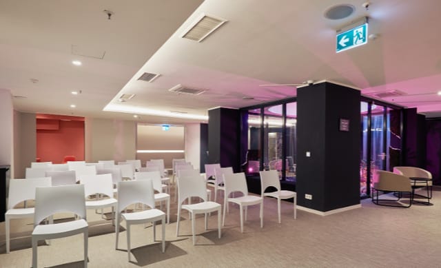 Modern event space at The Hangout Hub with white chairs, ideal for meetings and workshops.