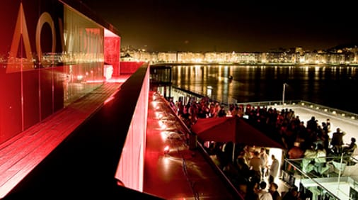 Thalassa Room at Aquarium San Sebastián, vibrant evening event with red lighting.