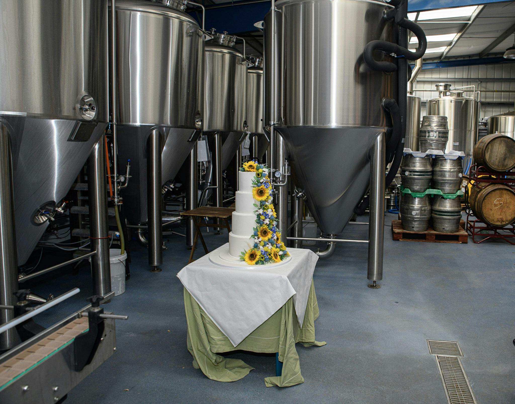 Wedding cake with sunflowers in unique brewery event space, ideal for celebrations.