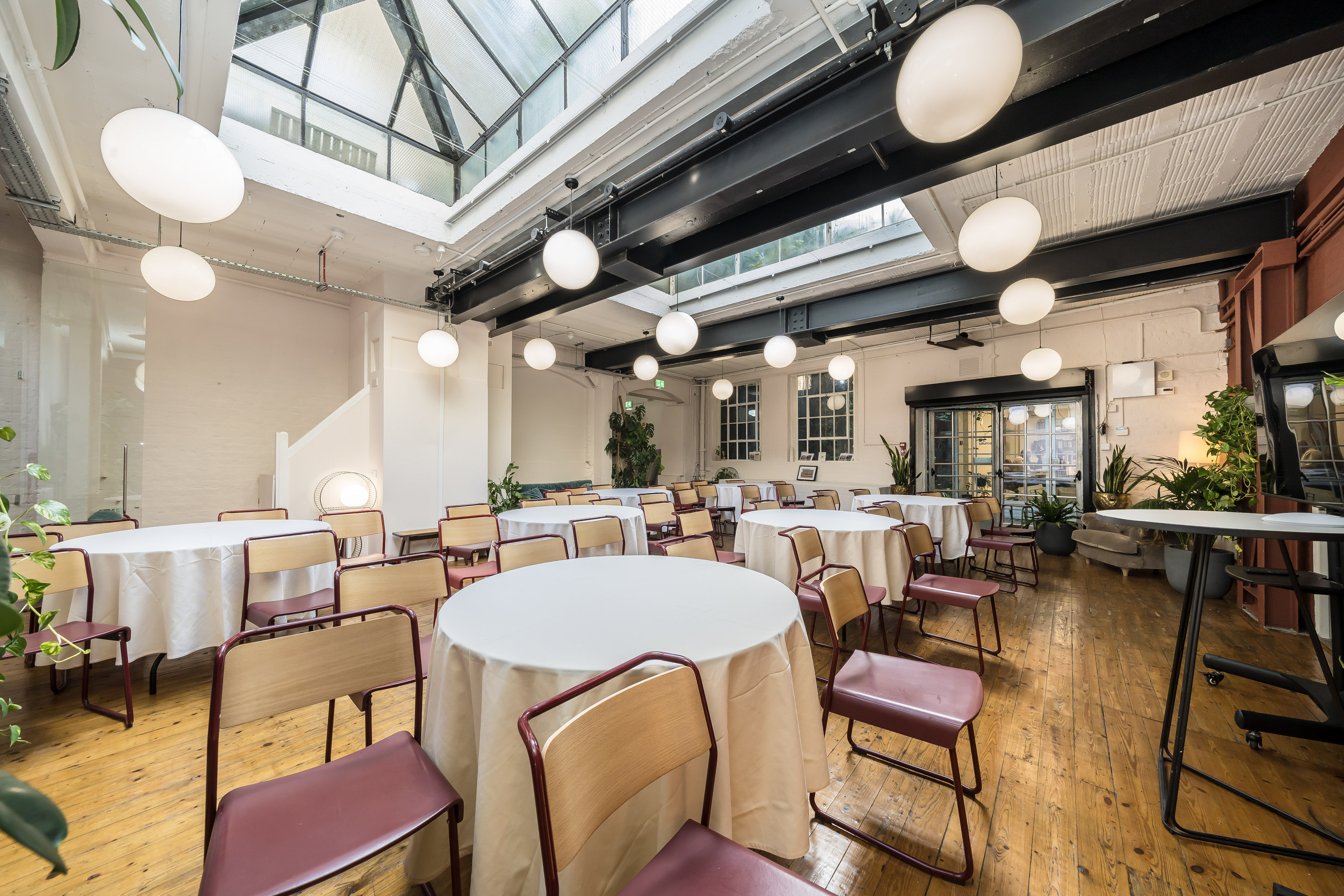 Elegant event space at Menier Playhouse with round tables and modern lighting. - Banner