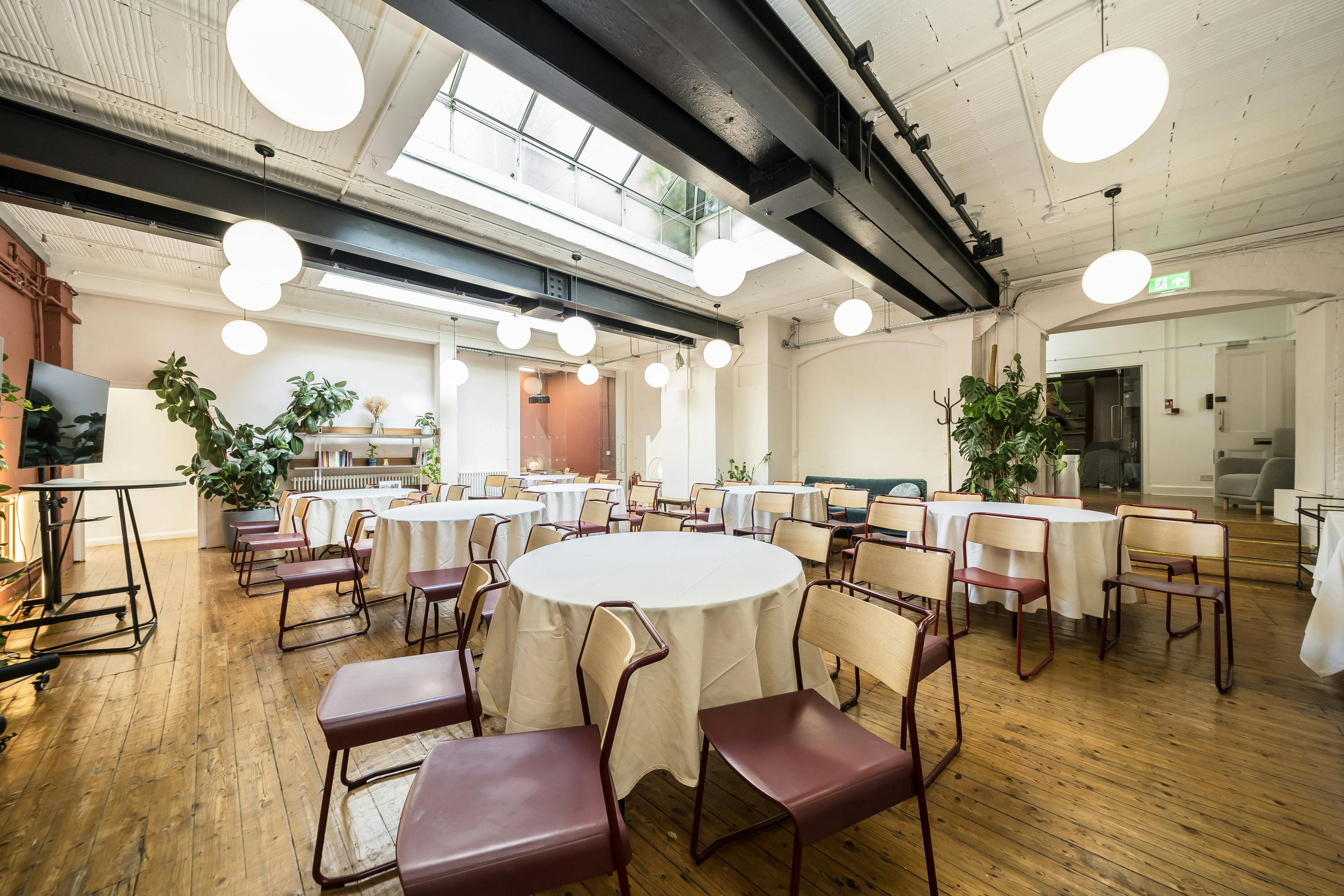 Versatile event space at Menier Playhouse with round tables, ideal for workshops and receptions.