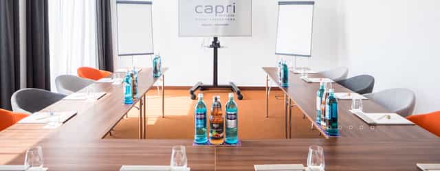 Meeting room setup for professional event with U-shaped tables and natural light.