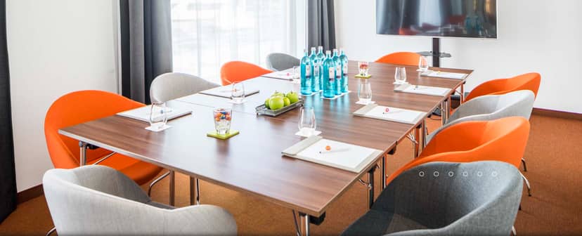 Professional meeting room with vibrant orange chairs for corporate events in Berlin.