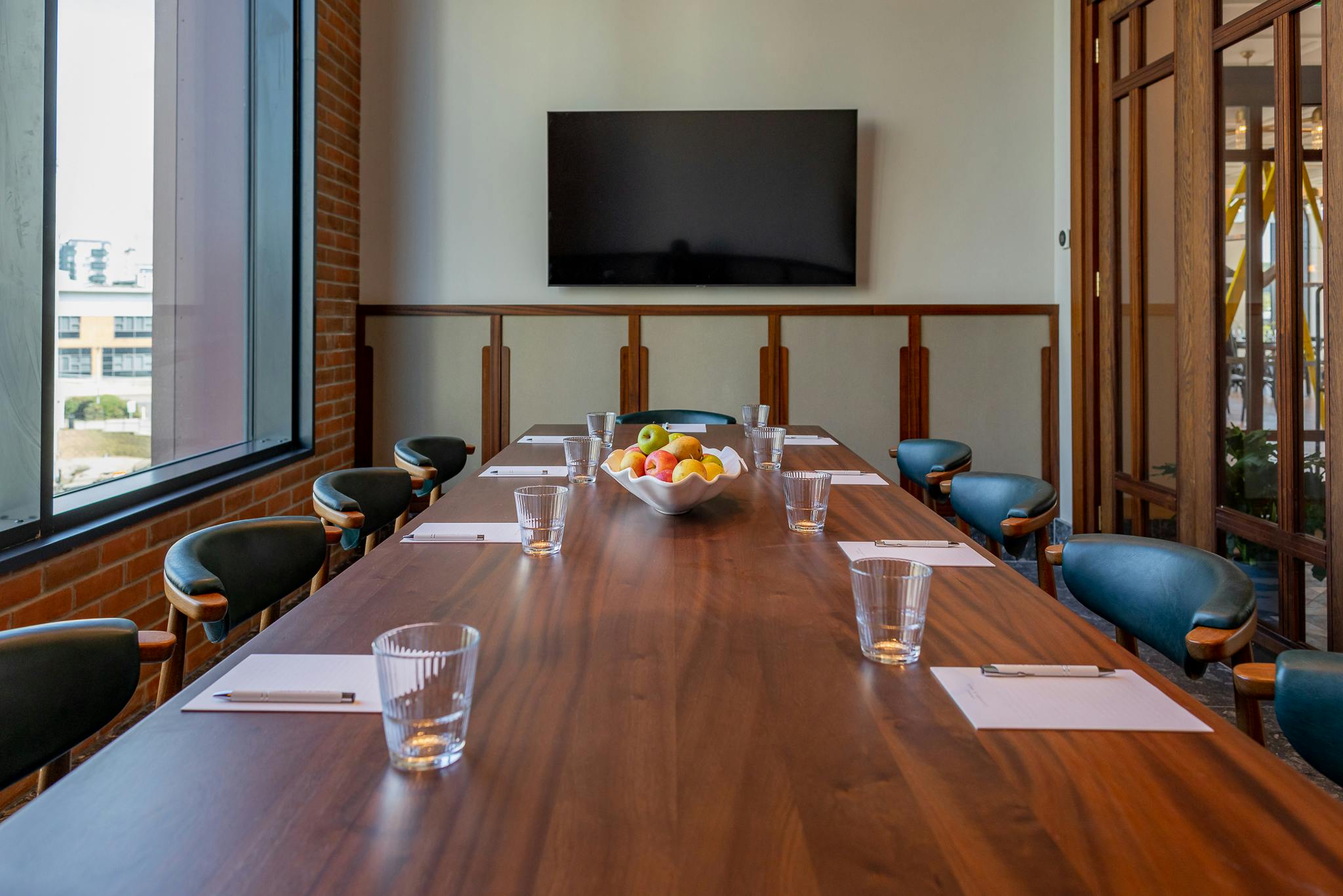 Modern conference room with wooden table, natural light, ideal for meetings and events.