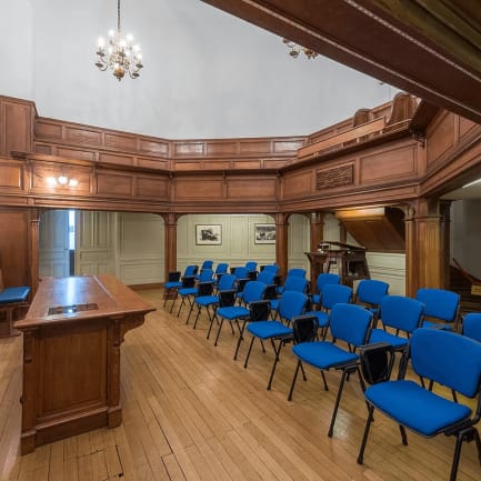 Elegant meeting room with wooden paneling, blue chairs for workshops and conferences.