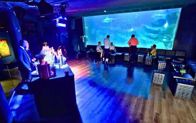 Stylish lounge with large aquarium backdrop for upscale networking events in Aquarium de Paris.