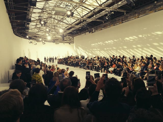 "Fashion runway event at Grande Verrière, Palais de Tokyo with vibrant lighting and engaged audience."