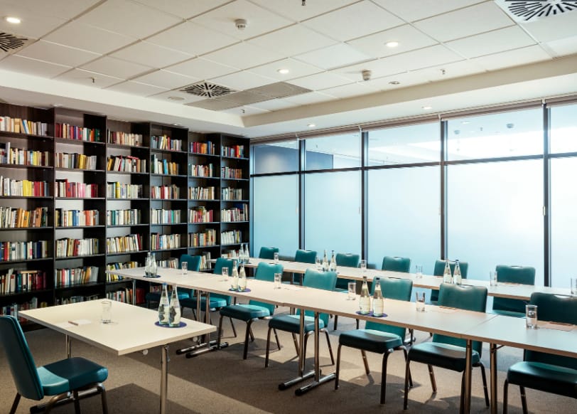 Meeting Room 1 at NH Berlin: modern space with teal chairs for workshops and strategy sessions.