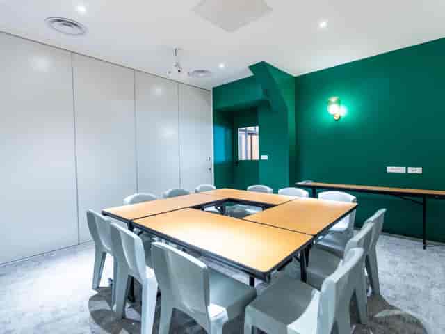 Versatile meeting room with modular table and vibrant green wall at Koven Coworking.