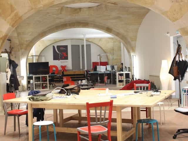 Versatile meeting space with wooden table and colorful chairs for creative workshops.