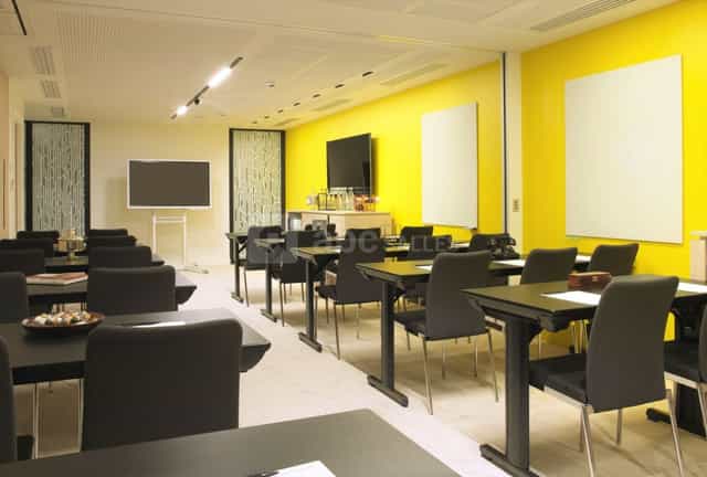 Modern meeting room with yellow walls, ideal for workshops and training events.