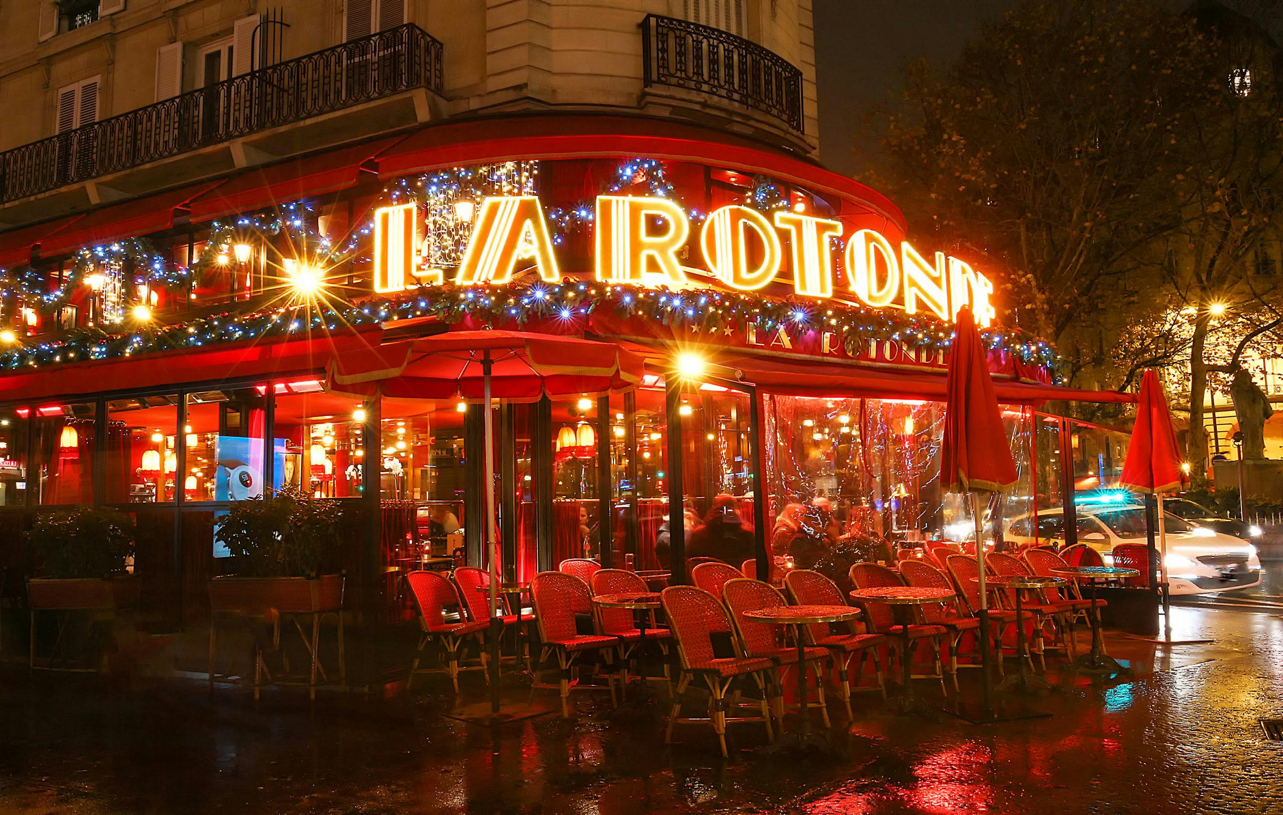 La Rotonde café in Paris, adorned with festive lights for evening events.