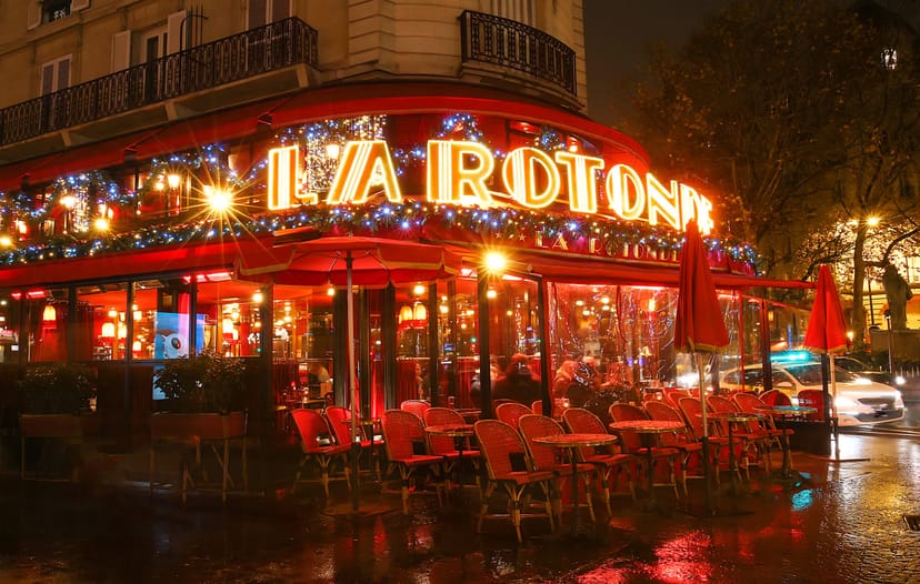 La Rotonde café in Paris, adorned with festive lights for evening events.