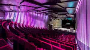Mirador Torre Glories event space with tiered seating and purple lighting for conferences.