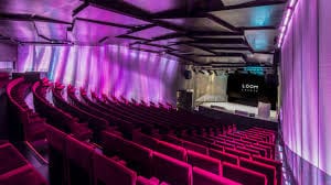Mirador Torre Glories event space with tiered seating and purple lighting for conferences.