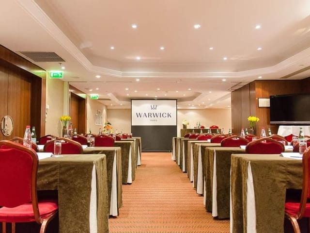 Corporate event meeting room with red chairs, ideal for workshops and presentations.