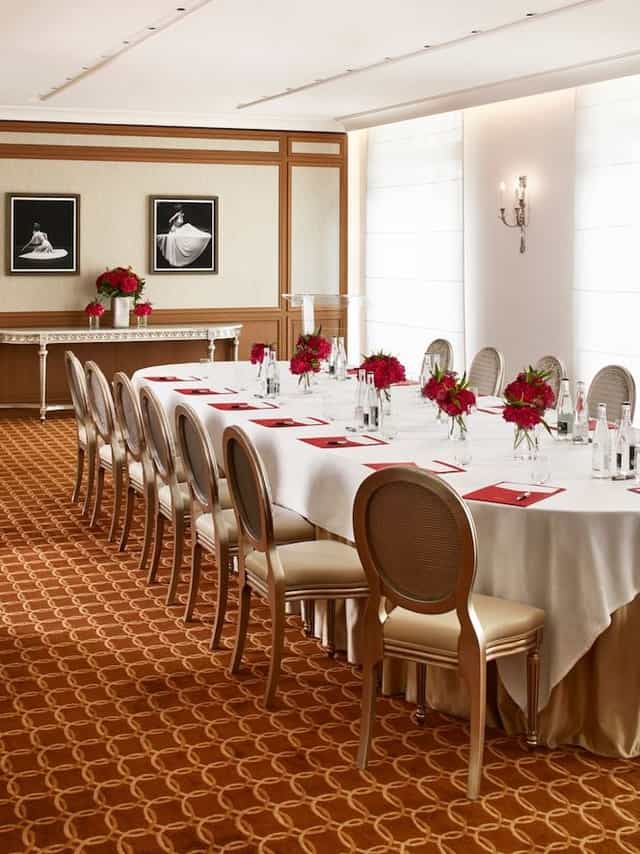 Elegant meeting room with red floral centerpieces at Hôtel Plaza Athénée event.