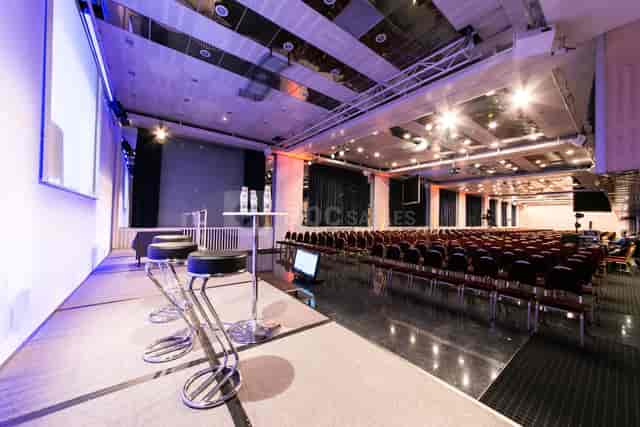 Conference room with stage and AV tech, ideal for seminars and conferences.