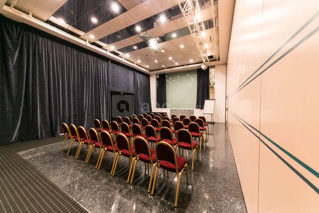 Conference room with red chairs and projection screen, perfect for presentations and workshops.
