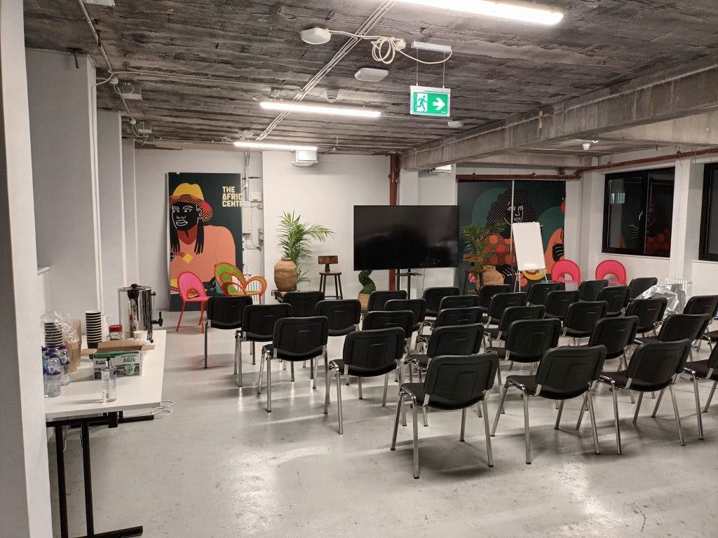 "Meeting space at The Africa Centre with chairs, screen, and vibrant artwork for workshops."