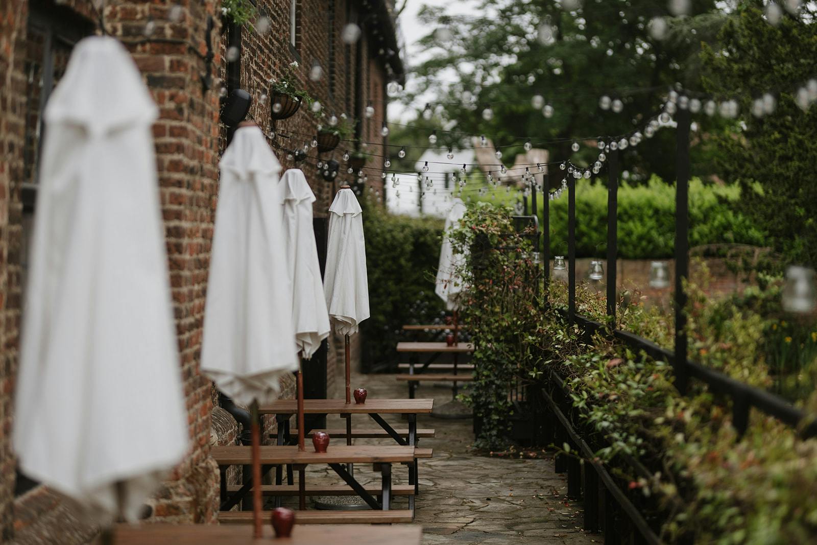 Moat Terrace at Tudor Barn Eltham: charming outdoor venue with rustic brick and white umbrellas.