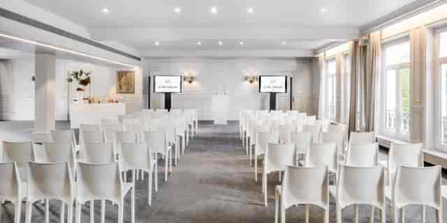 Louis XVI meeting space with white chairs, ideal for corporate conferences and events.