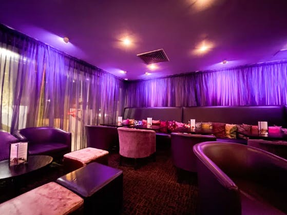 Stylish lounge at Zari Restaurant with soft purple lighting for intimate gatherings.