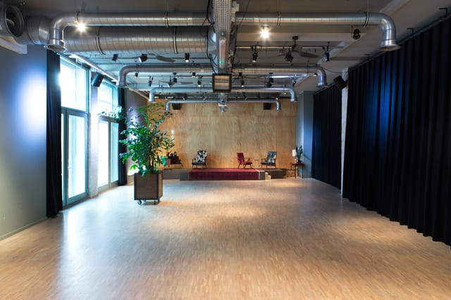 Versatile event space in Volkshotel with natural light, ideal for meetings and gatherings.