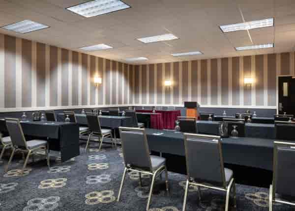 Meeting room with black tables, ideal for workshops and presentations at Regal Airport Hotel.