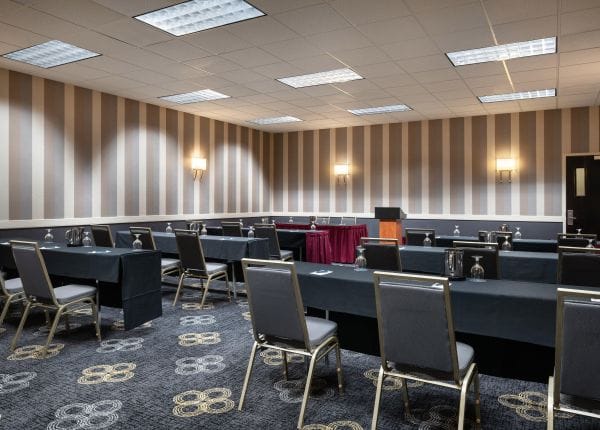 Meeting room with black tables, ideal for workshops and presentations at Regal Airport Hotel.