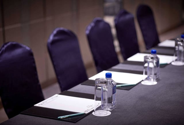 Meeting room setup at Dorsett Wanchai with sleek table, notepads, and elegant decor.