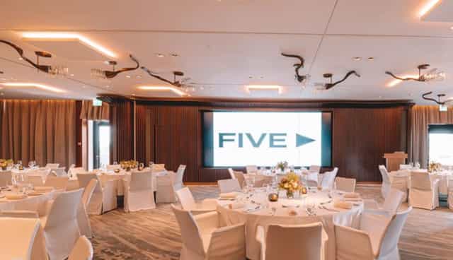 Elegant ballroom in FIVE Zurich, set for formal events with white linens and modern decor.