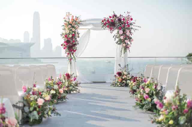 Outdoor wedding ceremony at Royal Hong Kong Yacht Club with floral arch and skyline.