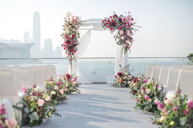 Outdoor wedding ceremony at Royal Hong Kong Yacht Club with floral arch and skyline.