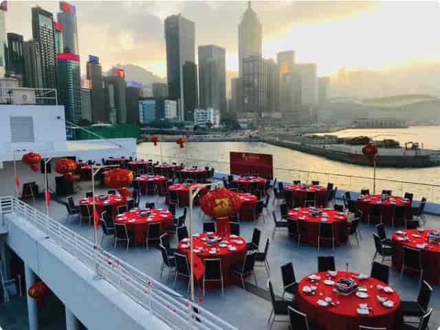 Rooftop event space at Royal Hong Kong Yacht Club with red linens and sunset skyline.