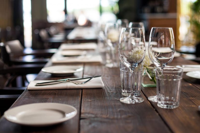 Corporate dinner party setup with polished glassware on a rustic wooden table.